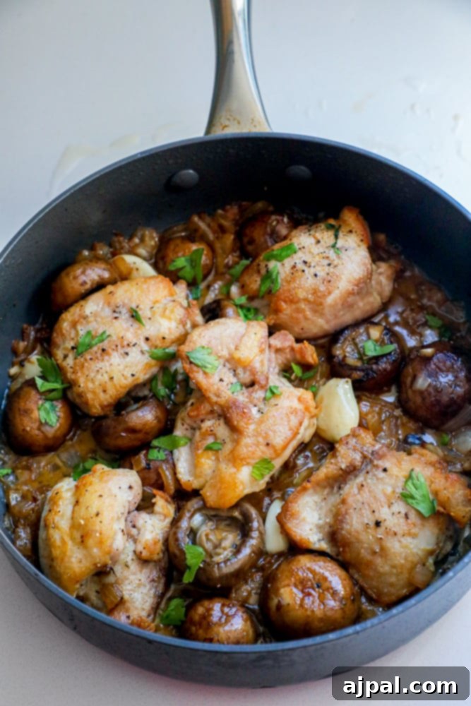 Quick One Pot Garlic Butter Chicken Thighs and Mushrooms 6 Close-up of a skillet filled with perfectly cooked keto chicken thighs and mushrooms in a rich garlic butter sauce.