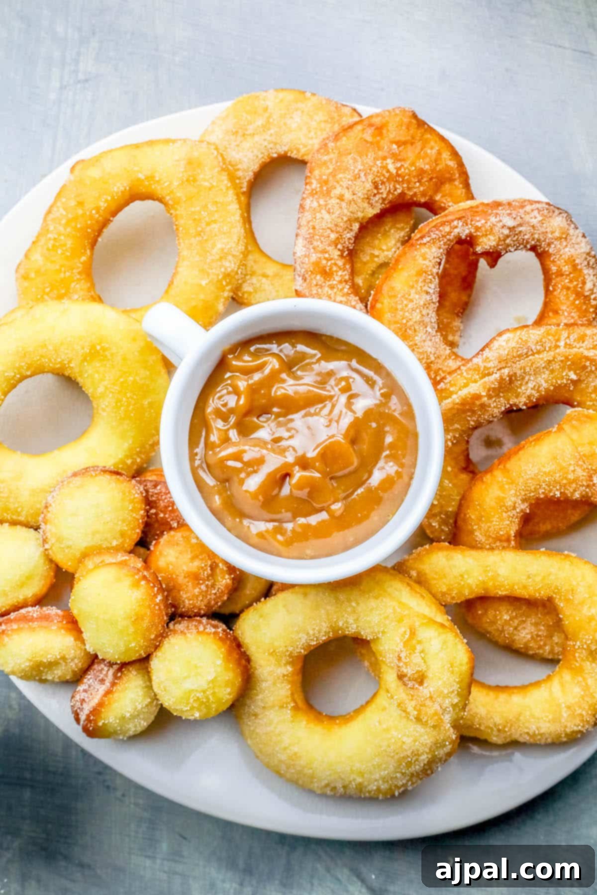 A close-up view of freshly fried homemade donuts made from canned biscuit dough, dusted with fragrant mulling spices. The warm, golden-brown texture is clearly visible, inviting a taste.