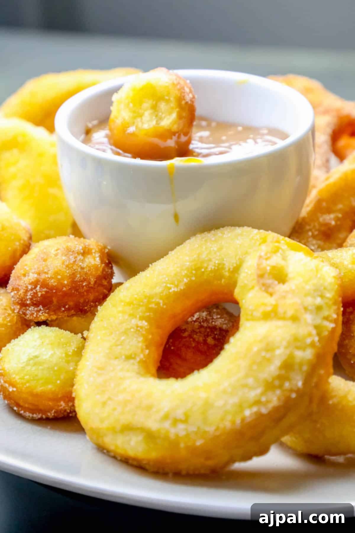 A captivating overhead shot of a stack of golden-brown 2-ingredient mulling spiced donuts, expertly fried and generously coated with a glistening sugary spice blend, ready to be enjoyed.