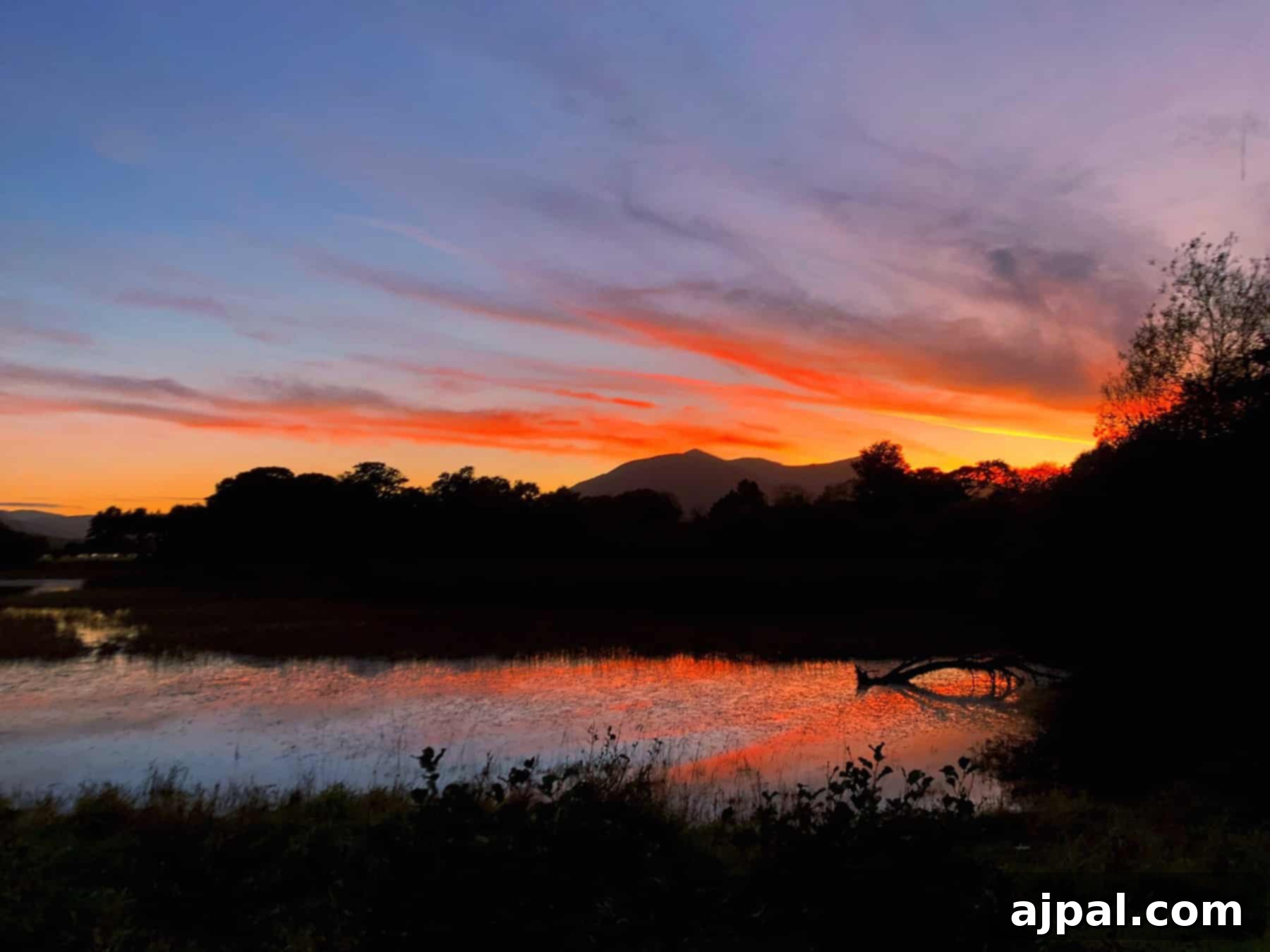 Uncovering Killarney Ireland's Gems 3 A beautiful sunset over a lake with mountains in the background, showcasing the breathtaking natural beauty of Killarney Ireland.