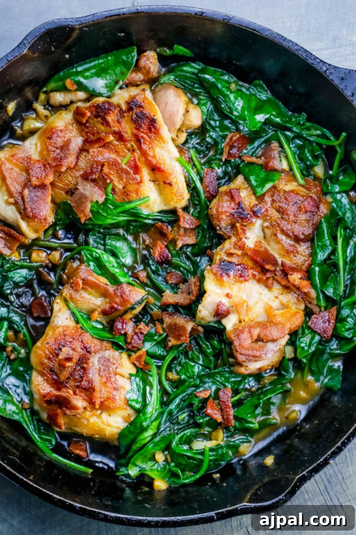 Easy Skillet Bacon Garlic Chicken and Spinach 7 Overhead view of the one-pot bacon garlic chicken and spinach dinner in a skillet, garnished with fresh herbs.