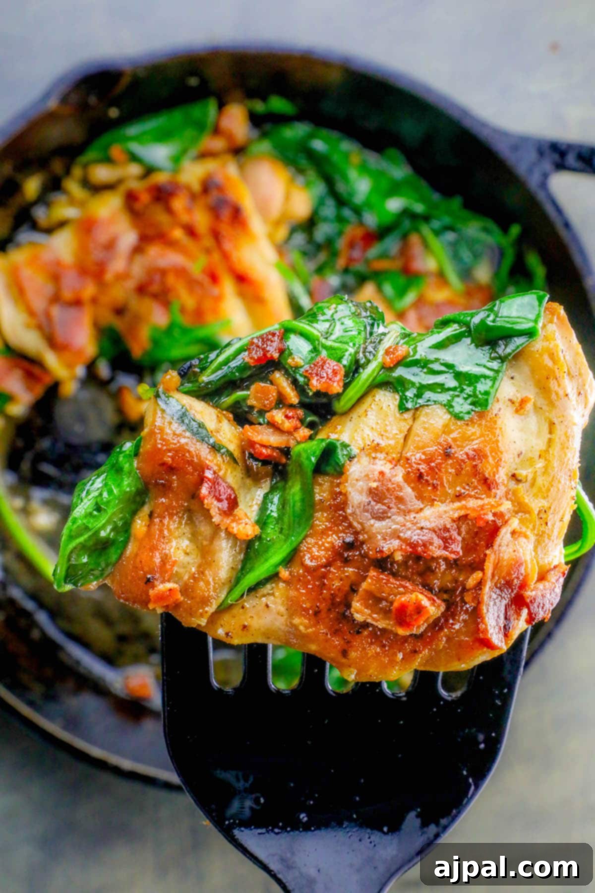 Easy Skillet Bacon Garlic Chicken and Spinach 8 A fork holding a piece of chicken with bacon and spinach from the one-pot dinner.