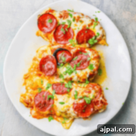 A plate of Cheesy Pizza Chicken garnished with herbs.