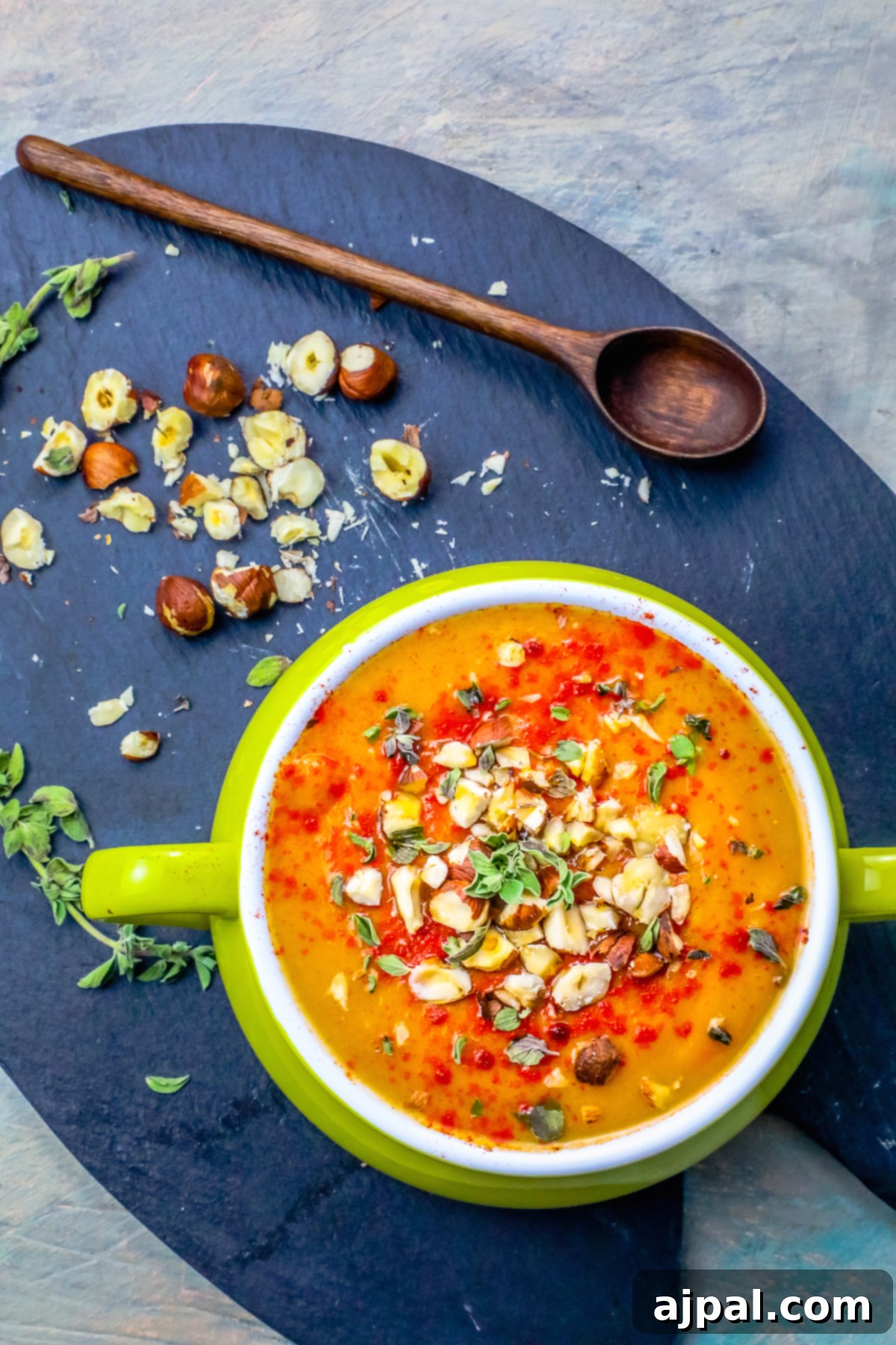 Velvety Sweet Potato Soup with Toasted Hazelnuts 6 A beautifully presented, creamy bowl of sweet potato soup, generously topped with a sprinkle of toasted nuts and almonds, evoking warmth and comfort.