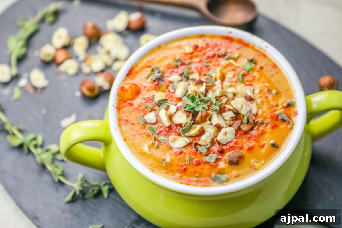 Velvety Sweet Potato Soup with Toasted Hazelnuts 3 A vibrant green bowl filled with creamy sweet potato soup, generously topped with toasted nuts and fresh herbs.