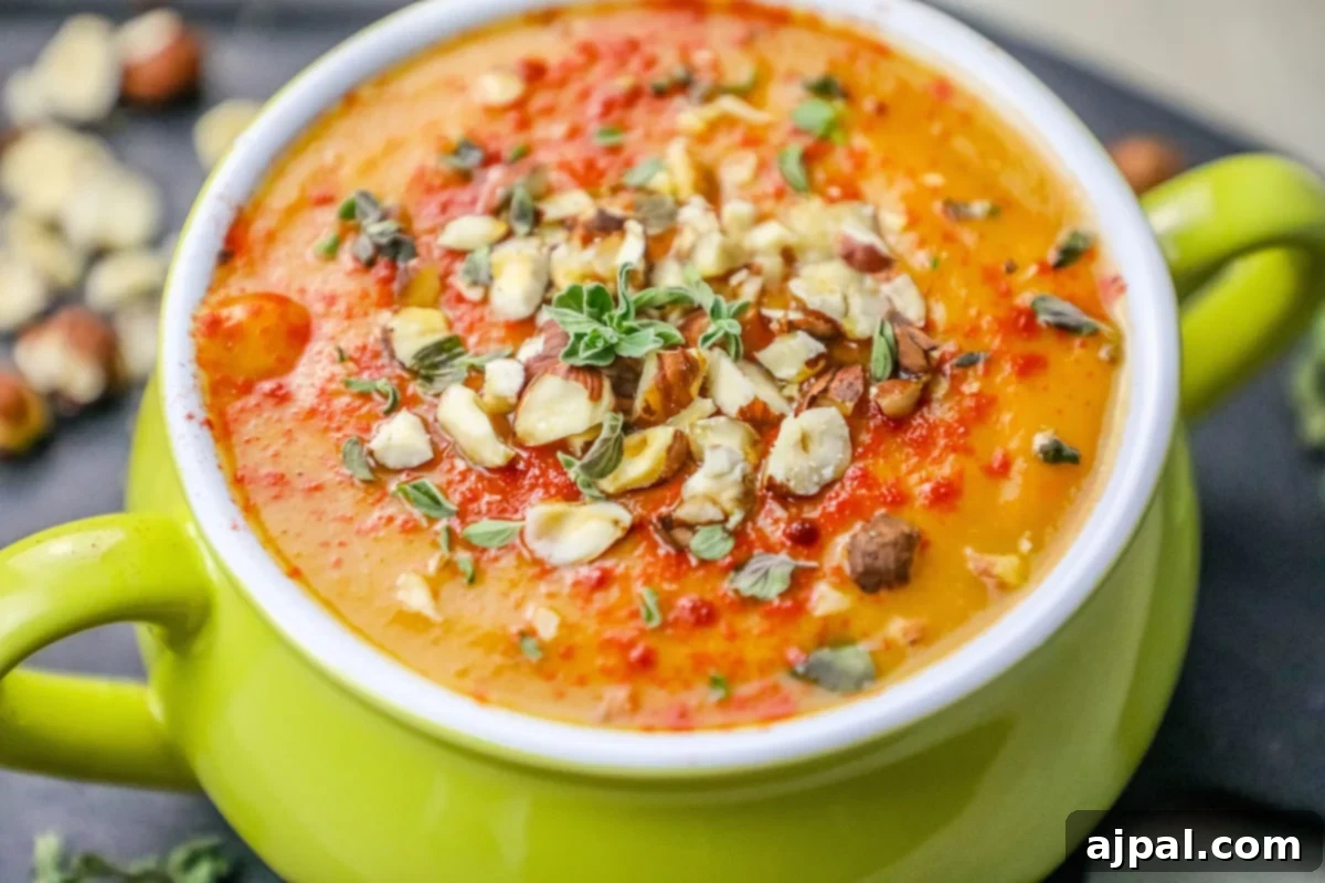 Velvety Sweet Potato Soup with Toasted Hazelnuts 4 A rich, creamy sweet potato bisque served in an elegant green bowl, adorned with a generous sprinkle of toasted hazelnuts.