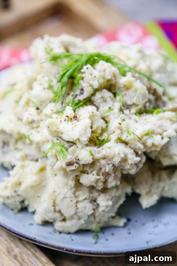 Close-up of fluffy Instant Pot mashed potatoes, generously seasoned with fresh dill, salt, and freshly cracked pepper.