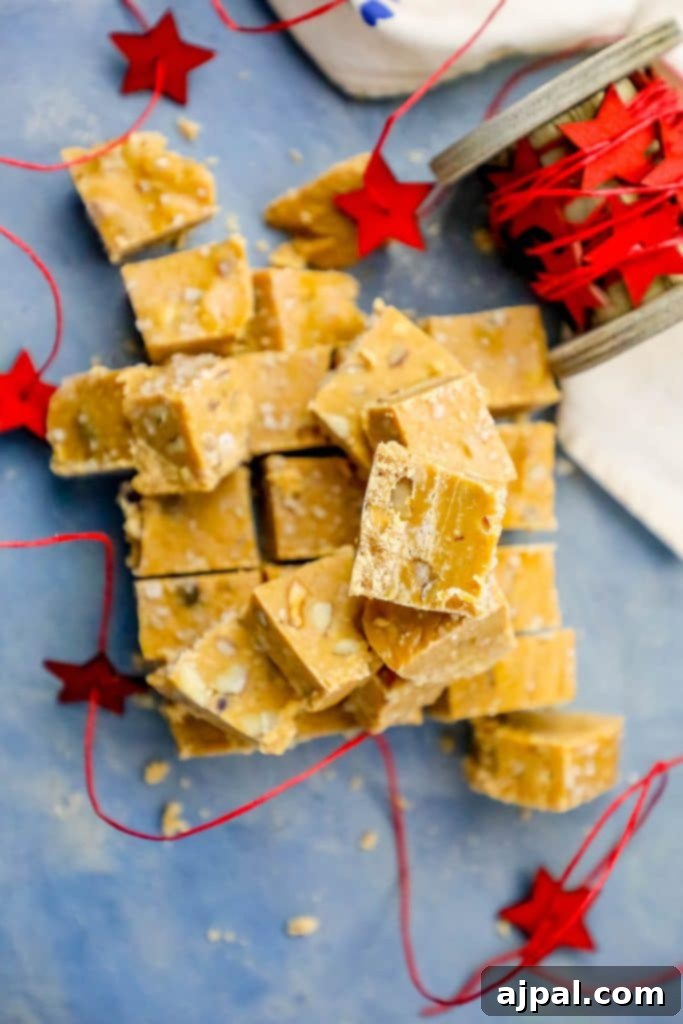 Luscious Butterscotch Walnut Slow Cooker Fudge 4 A delectable mountain of rich Walnut Butterscotch Fudge pieces, beautifully showcasing the smooth texture and embedded walnuts, on a vibrant blue surface.