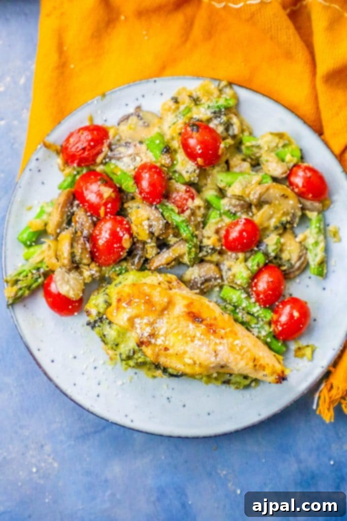spinach and artichoke dip stuffed chicken next to a mushroom, tomato, and asparagus salad.
