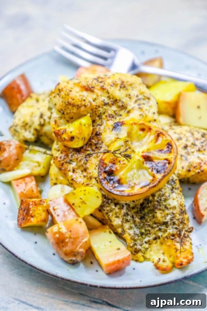 A plate with lemon garlic chicken and potatoes on it, garnished with fresh herbs and lemon slices.