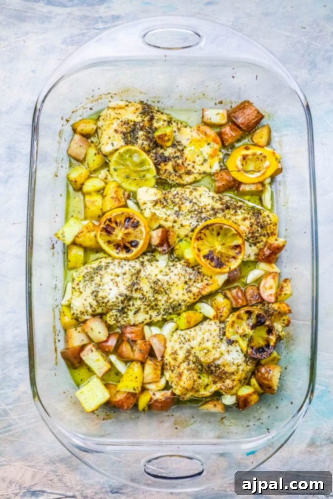 A glass baking dish with fish, potatoes and lemons prepared using a lemon garlic chicken and potatoes recipe.