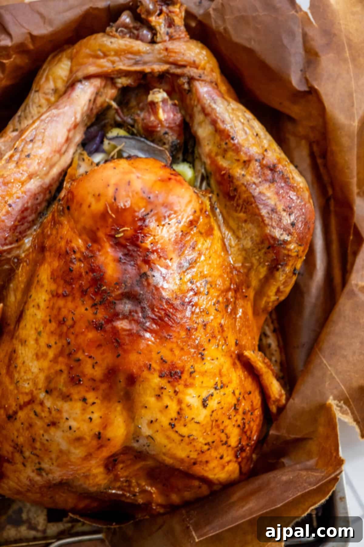 Flavorful Herb Roasted Turkey in a Bag 2 Roasted turkey with crispy, golden-brown skin on parchment paper, seasoned with herbs—try this easy Brown Bag Herb Roasted Turkey Recipe for perfectly juicy meat.