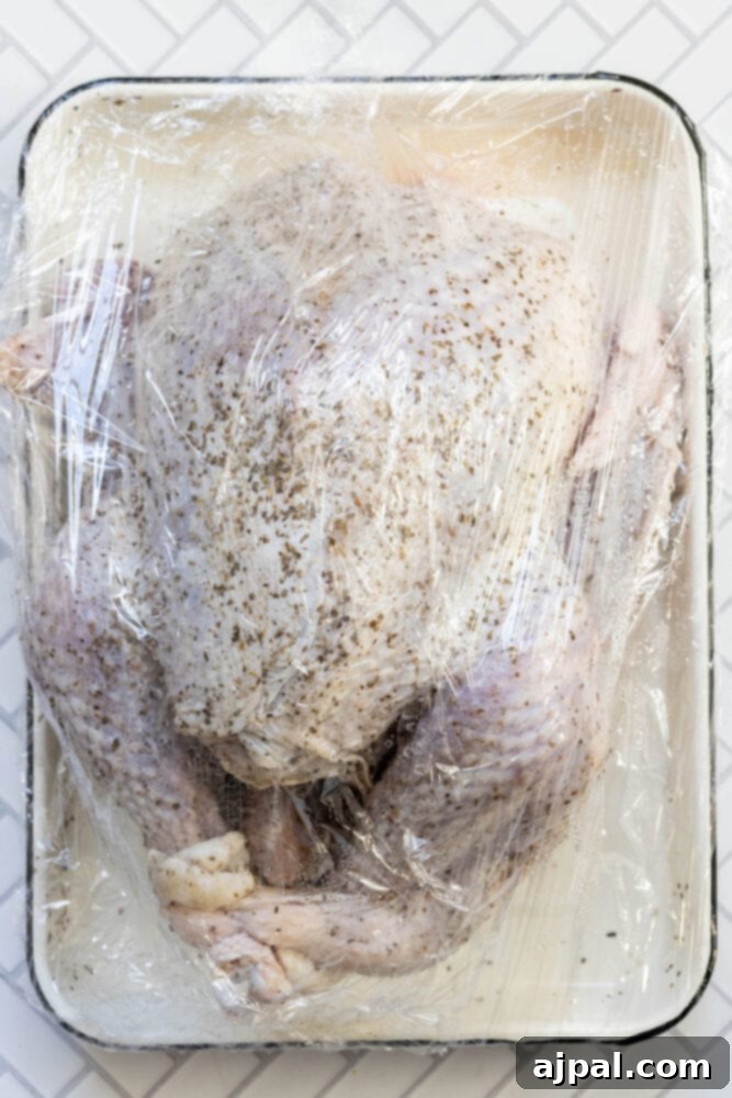 Flavorful Herb Roasted Turkey in a Bag 6 picture of turkey dry brining in plastic wrap on a white tray