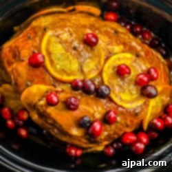 Slow Cooker Ham with Zesty Orange Cranberry Ginger Glaze 10 Cooked ham in a slow cooker with orange slices and cranberries on it