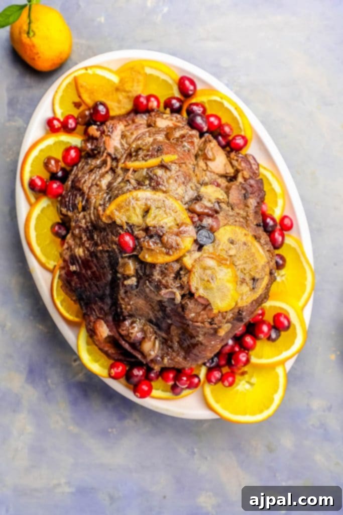 Slow Cooker Ham with Zesty Orange Cranberry Ginger Glaze 3 Close-up of a succulent slow cooker ham, richly glazed with orange and cranberries, ready to be served.