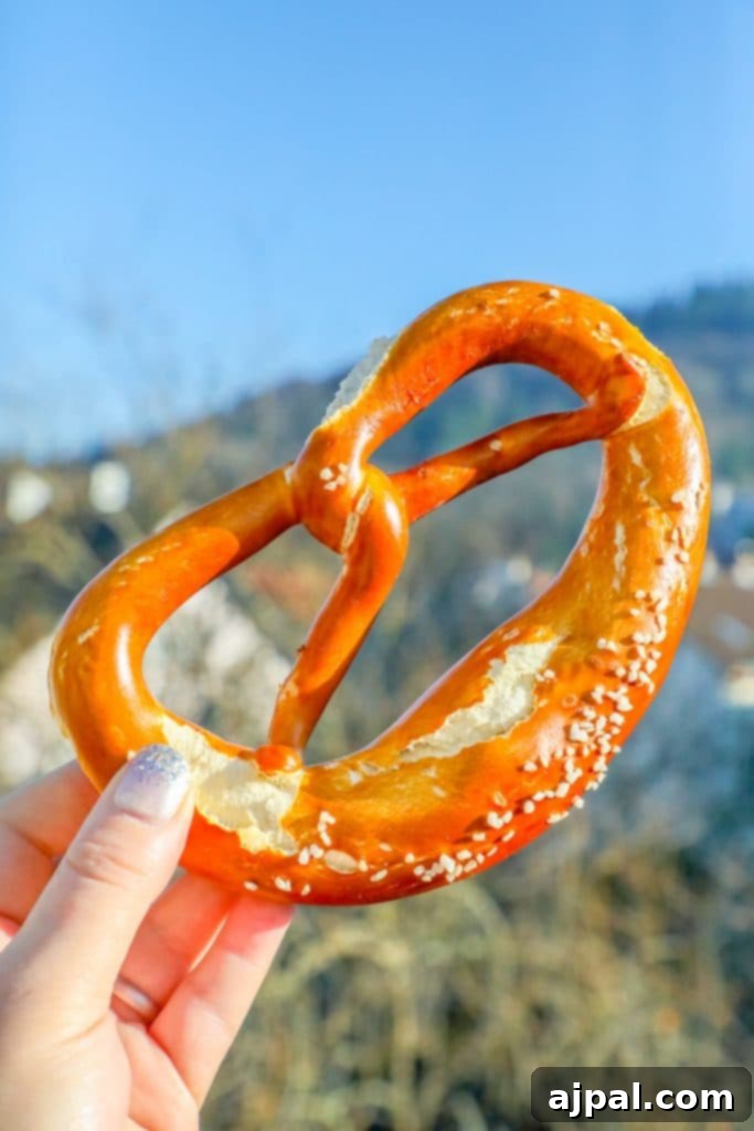 A person holding a giant German pretzel (bretzel) at a bustling Christmas Market, ready to enjoy.