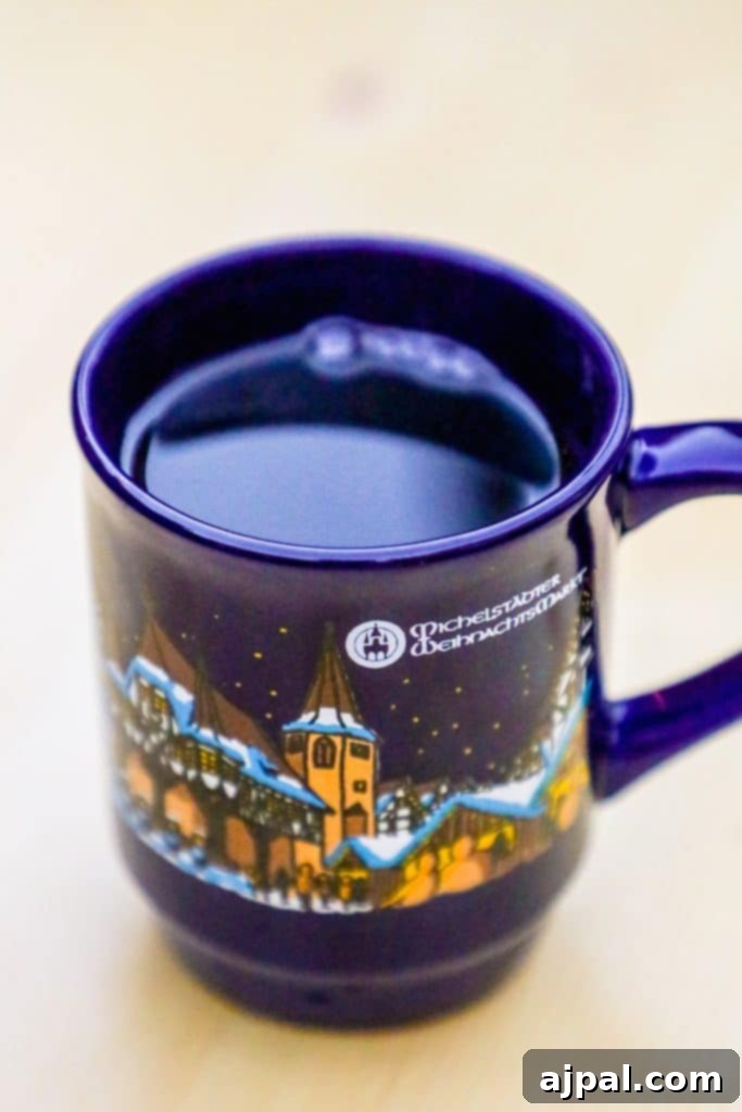 Top 10 Reasons to Explore a Christmas Market 7 A charming ceramic mug filled with steaming mulled wine, adorned with a festive snow scene, from a European Christmas Market, evoking warmth and holiday spirit.