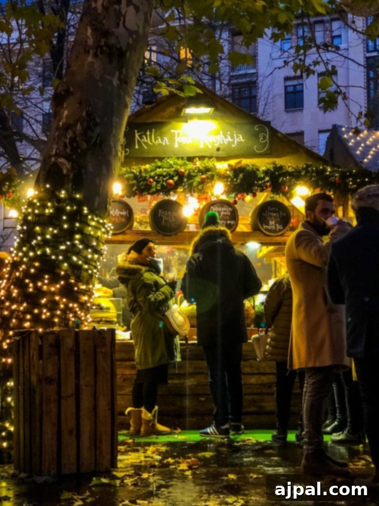 People enjoying the festive atmosphere around a bustling Christmas market stall adorned with bright Christmas lights, possibly after an ice skating session.