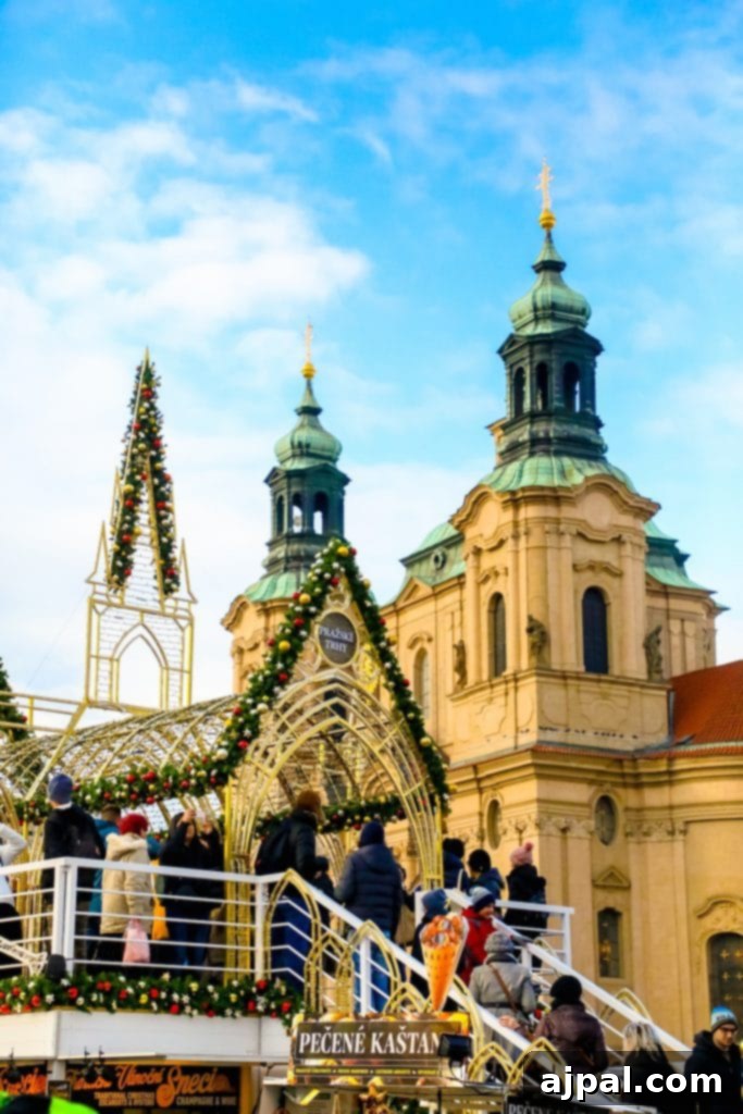 A festive Christmas market in Prague, with a historical building adorned with lights and a crowd enjoying the atmosphere