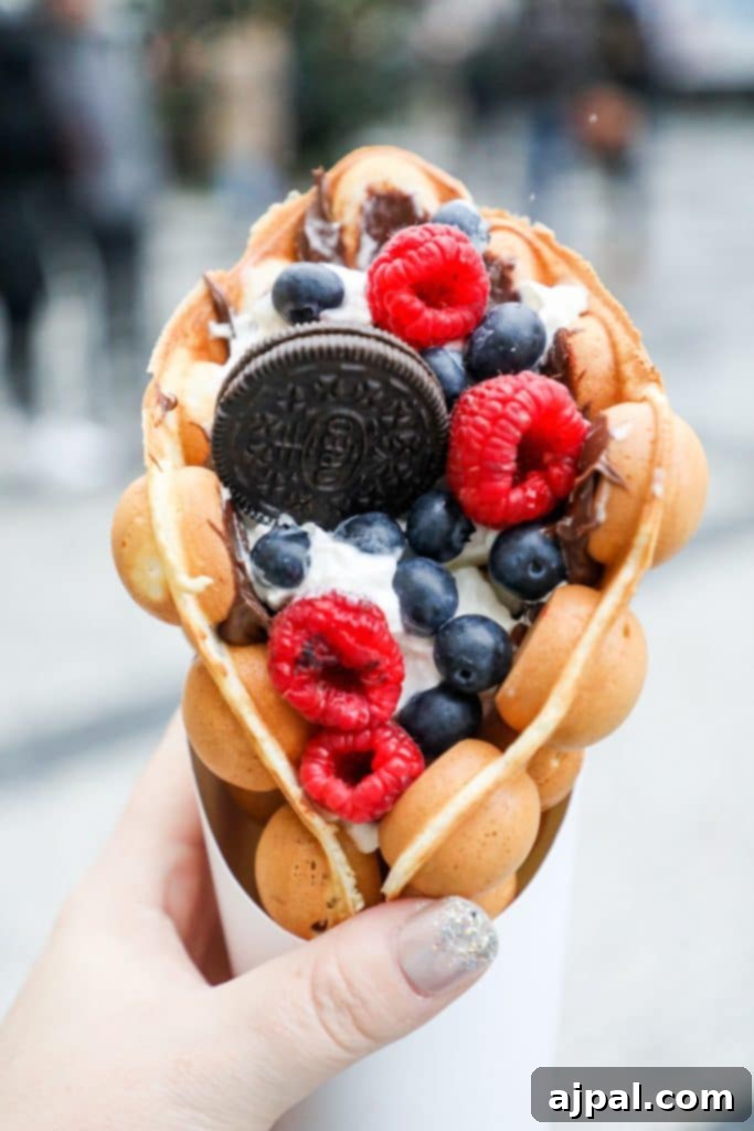 A delicious bubble waffle cone topped with fresh berries and Oreo crumbles, a popular treat in Prague