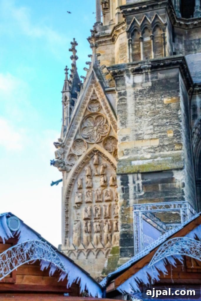 A snow-covered Notre-Dame Cathedral in Reims, France, with a Christmas market stall in the foreground