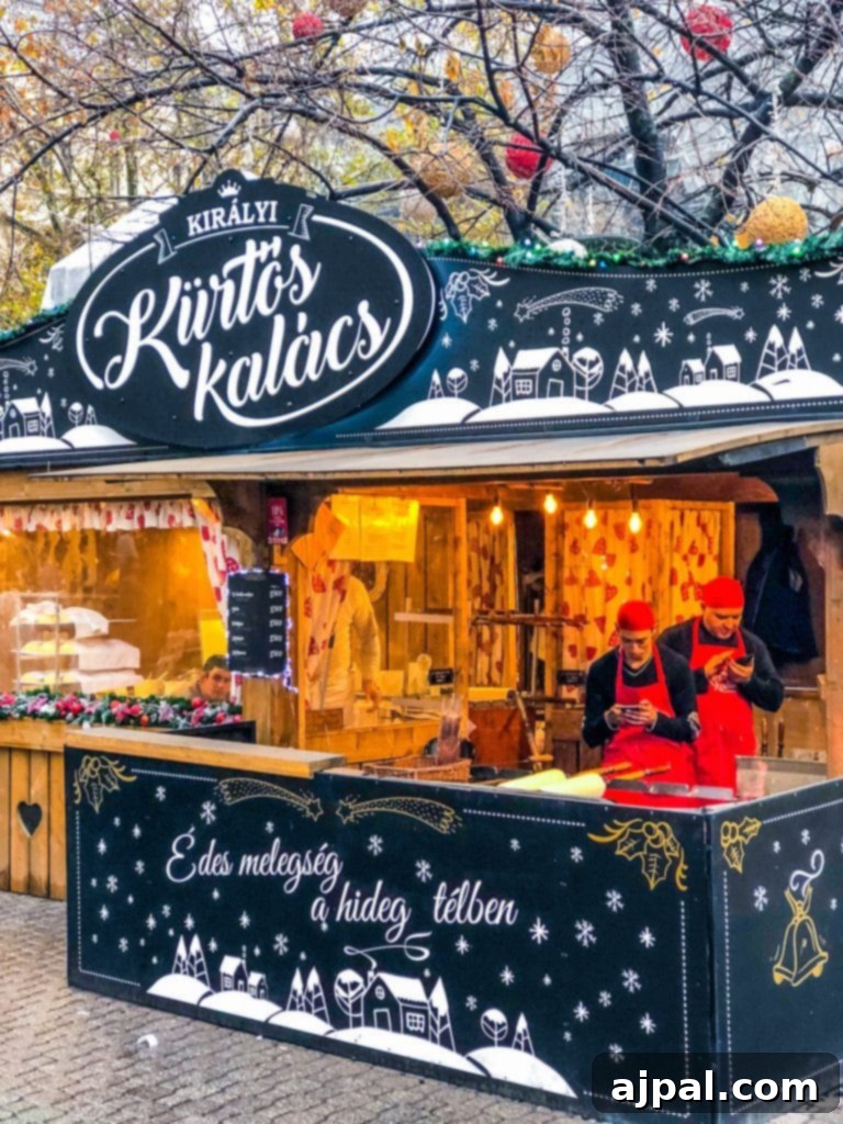 A festive chimney cake (Kurtos Kalacs) stand at a Budapest Christmas market, adorned with lights
