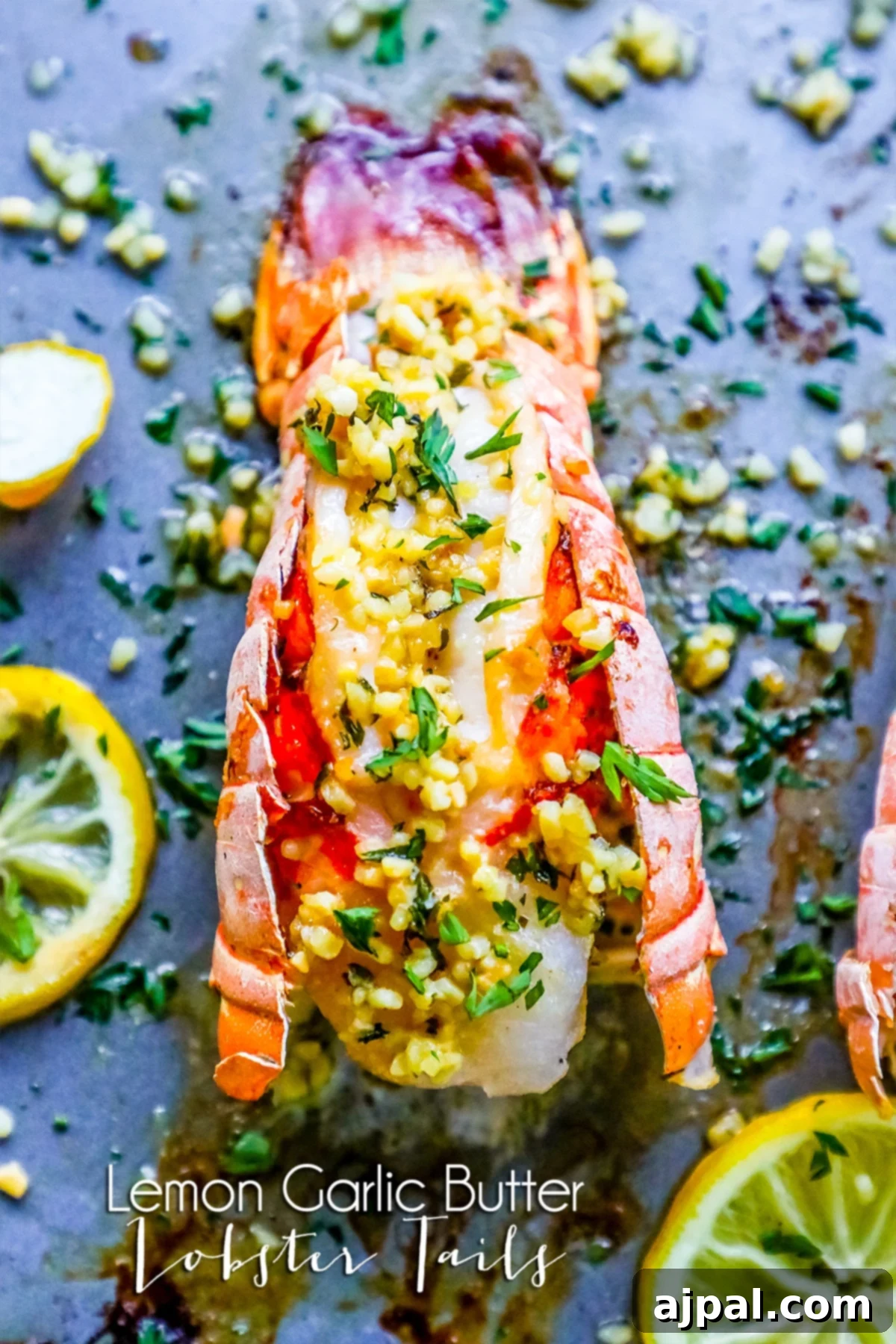 Close-up of perfectly broiled lobster tails garnished with fresh lemon wedges and parsley on a baking sheet, ready to serve.