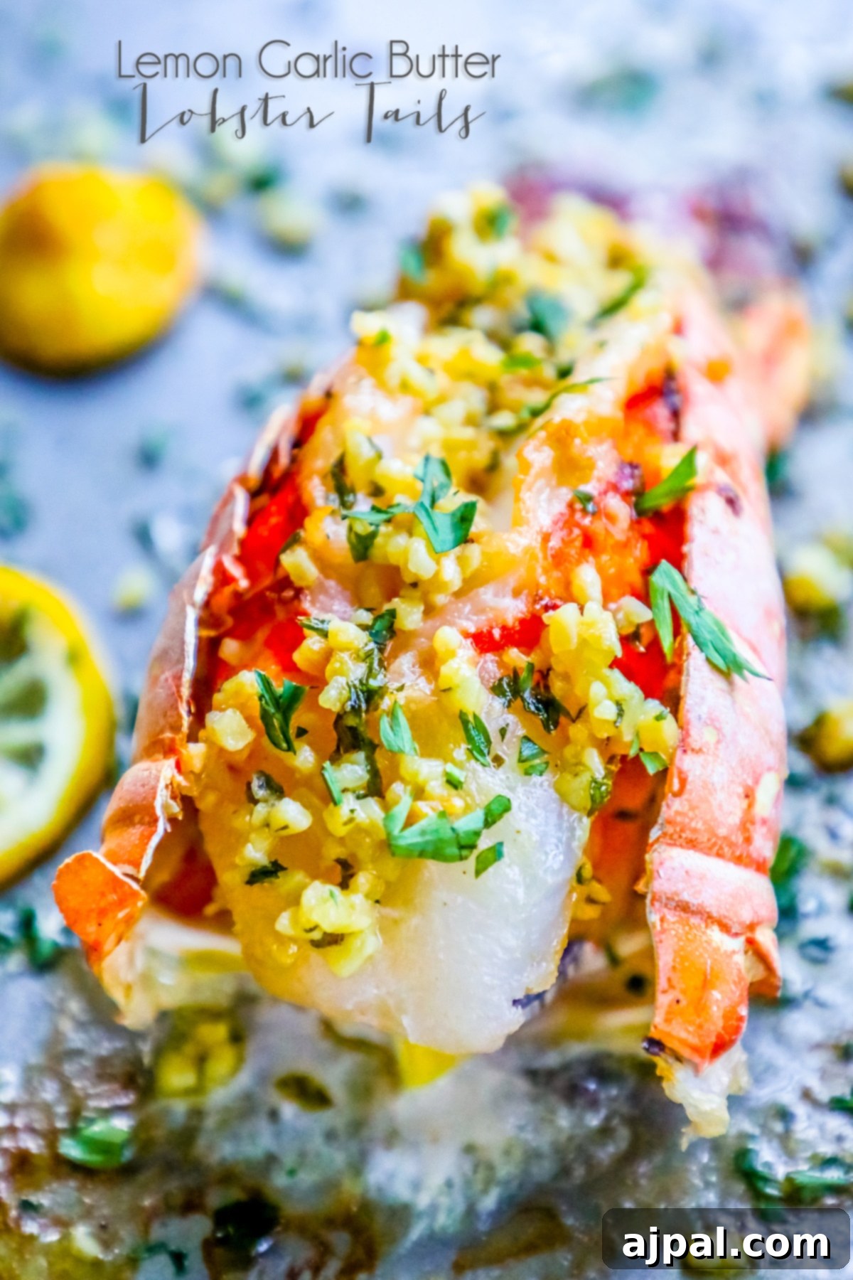 Two exquisitely prepared lemon garlic butter lobster tails, garnished with fresh herbs, resting on a baking sheet, ready for serving a romantic dinner.