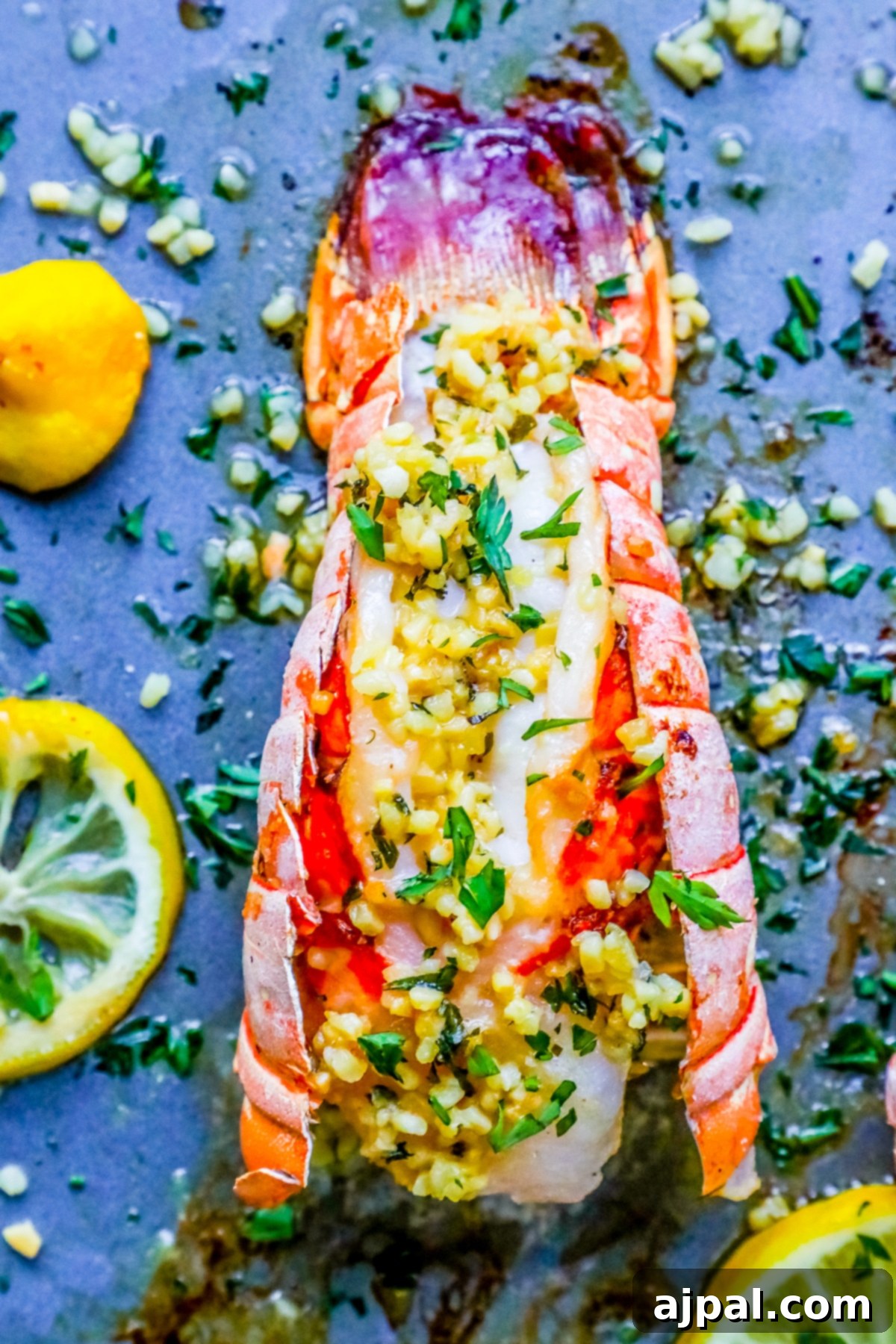 Three perfectly broiled lobster tails glistening with lemon garlic butter, garnished with fresh herbs and lemon wedges, ready to be served.
