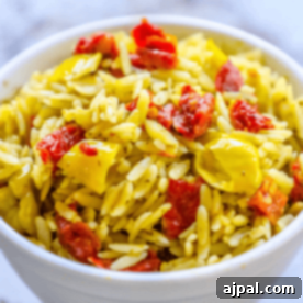 Orzo with sun-dried tomatoes and basil pesto in a serving bowl.