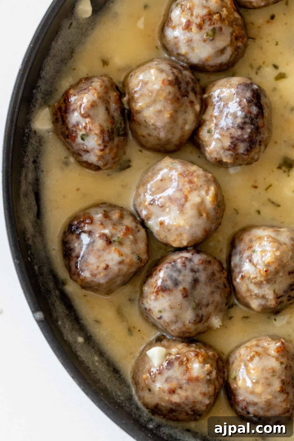A pan filled with Easy Keto Diet Meatballs in creamy sauce, browned and partially submerged, creating a rich and indulgent one-pot keto dinner.