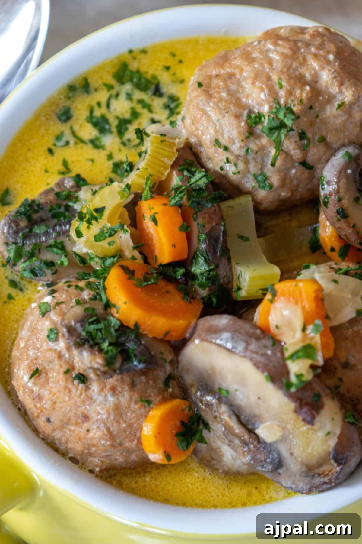 Rich & Creamy One-Pot Meatball Delight 2 A bowl of one pot creamy meatball soup with tender carrots, mushrooms, and a garnish of chopped parsley swimming in a luscious broth.