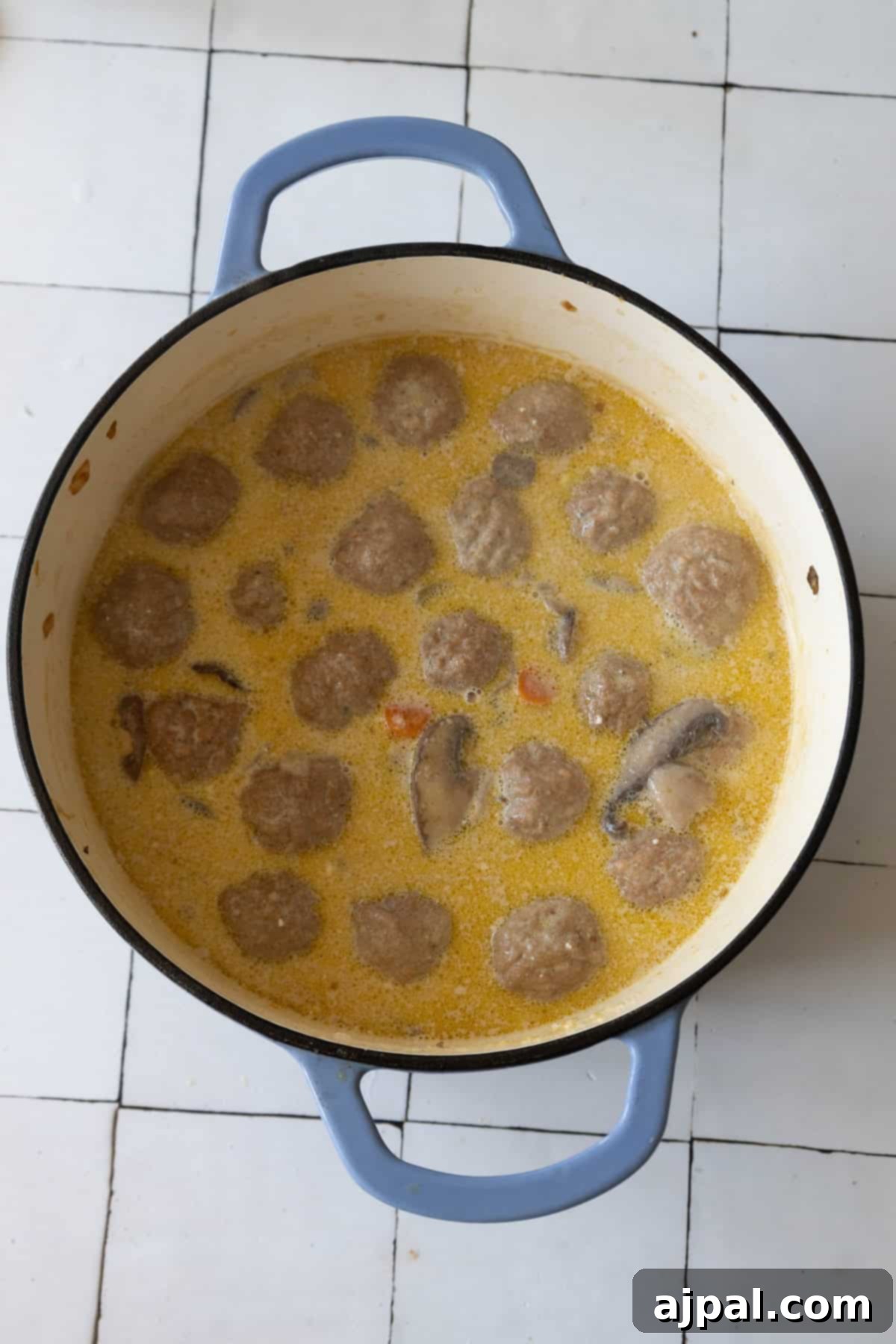 Rich & Creamy One-Pot Meatball Delight 9 A pot filled with savory meatballs and sliced mushrooms in a creamy yellow broth, capturing the essence of a perfect one pot creamy meatball soup.