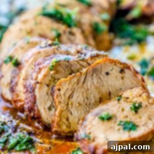 picture of sliced baked pork tenderloin topped with parsley on aluminum foil