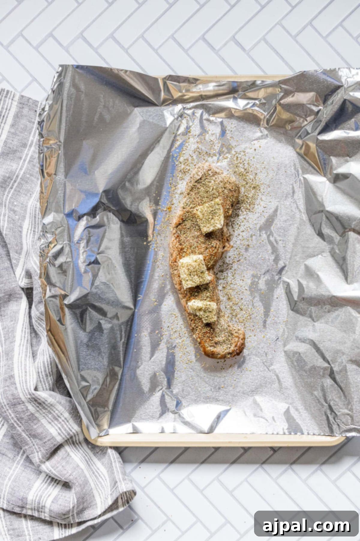 Your New Favorite Baked Pork Tenderloin 7 browned pork tenderloin on a piece of foil on a baking sheet