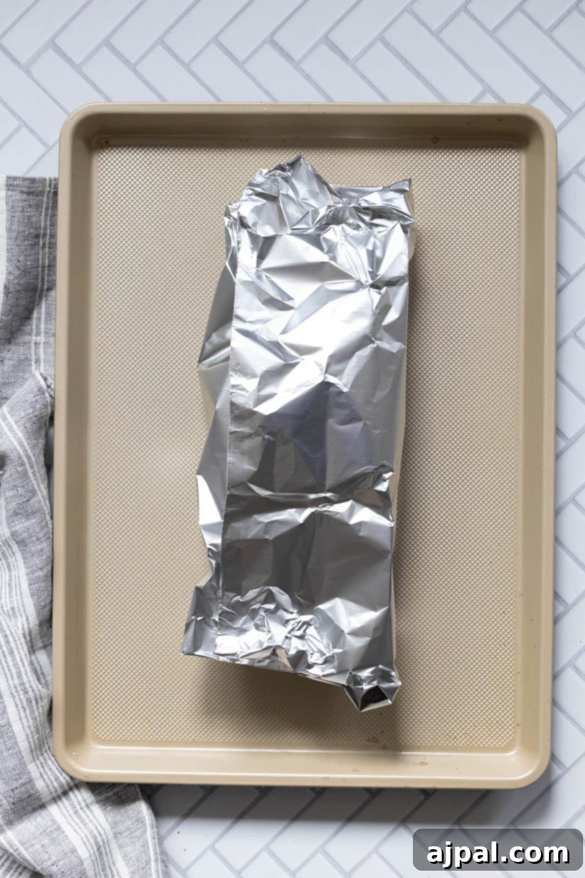 Your New Favorite Baked Pork Tenderloin 8 pork tenderloin wrapped in foil on a baking sheet