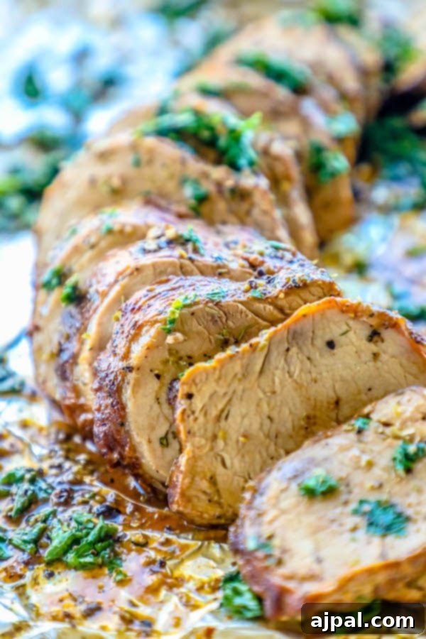 Your New Favorite Baked Pork Tenderloin 10 Picture of pork tenderloin sliced and garnished with parsley on tinfoil.