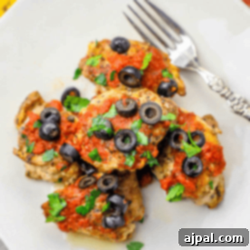 Chicken breasts topped with salsa and olives on a plate.