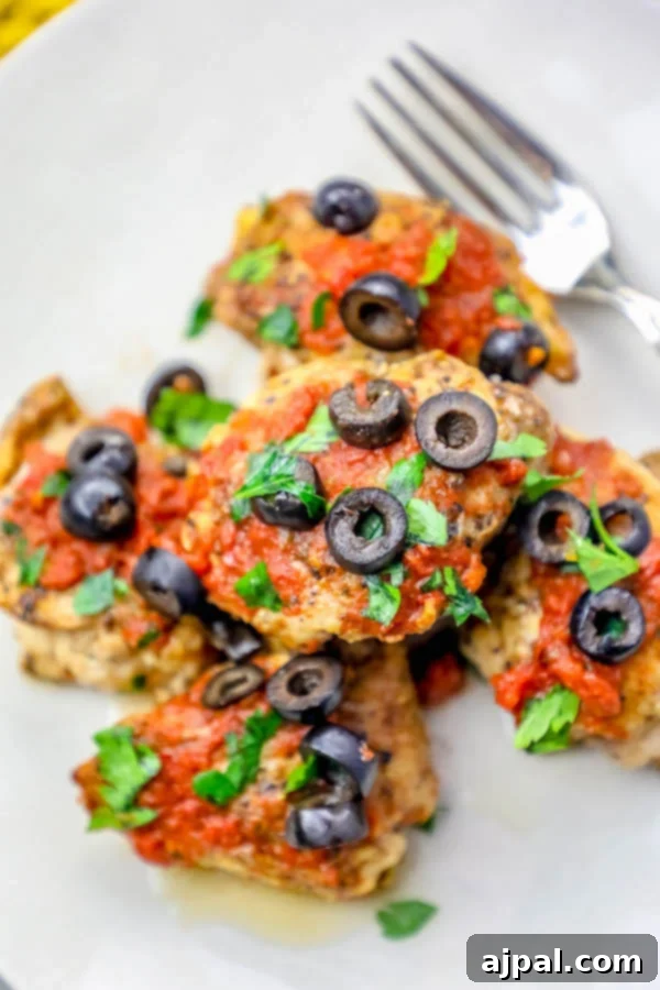 A vibrant plate of Mexican chicken thighs, adorned with olives and tomatoes, showcasing a rich and inviting culinary presentation.