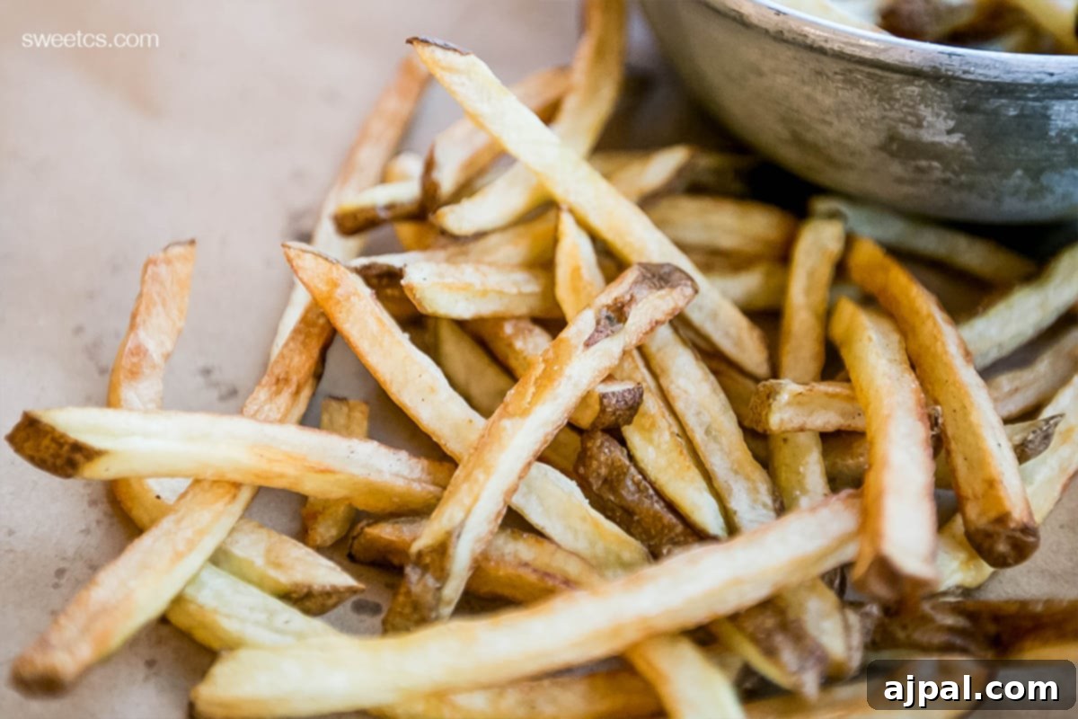 Golden Crispy Oven Fries 4 A bowl of french fries served with a dip on a wooden table.