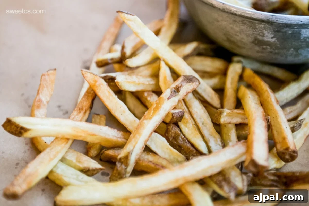 Crispy Oven Fries 4 A vibrant bowl of crispy French fries served with a small side of dipping sauce, highlighting the perfect golden texture.