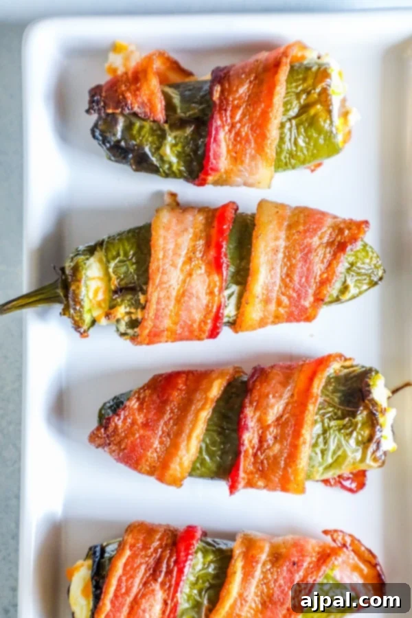 Bacon-Wrapped Garlic Cheddar Jalapeno Poppers 2 picture of bacon wrapped jalapeno poppers on a plate