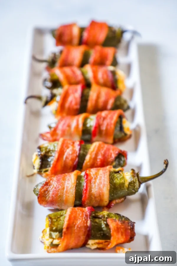 Bacon-Wrapped Garlic Cheddar Jalapeno Poppers 3 picture of bacon wrapped jalapeno poppers on a plate
