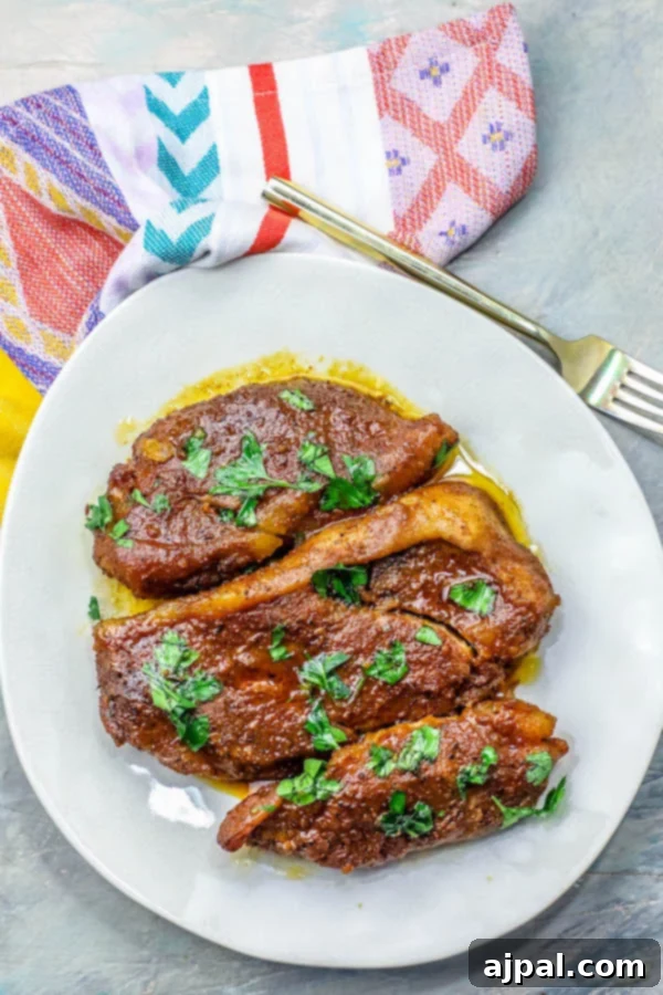 Fall-Apart Tender Crock Pot Pork Steaks 5 picture of pork steaks on a white plate with a bright colored napkin and fork