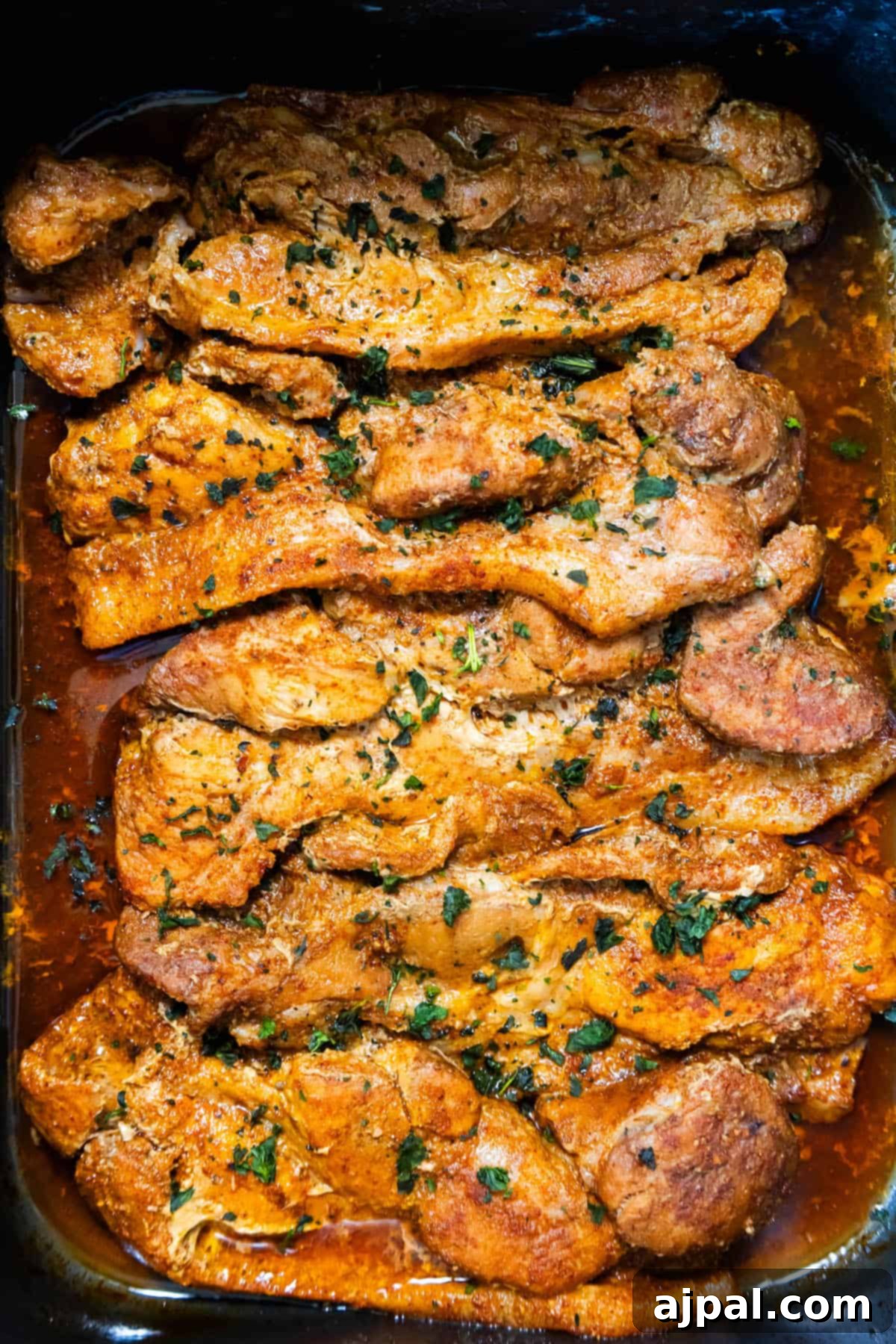 Fall-Apart Tender Crock Pot Pork Steaks 9 Slow cooker pork chops in a dish with sauce, cooked using a crock pot.