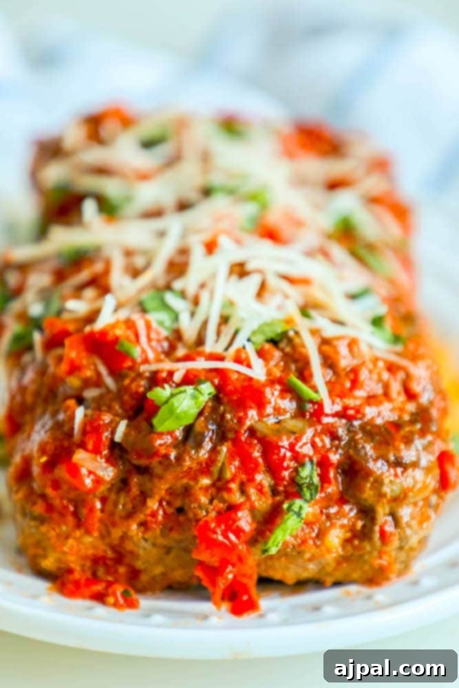 A delicious slice of Italian meatloaf baked in marinara sauce and topped with melted cheese, served on a white plate with fresh herbs. This image perfectly captures the rich, moist, and flavorful nature of the dish, highlighting its appeal as an easy, low-carb, and gluten-free family meal.