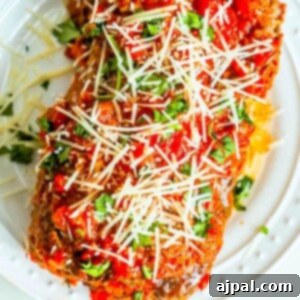 Meatloaf with marinara sauce and parmesan cheese on a white plate, the best easy baked Italian meatloaf recipe ever.