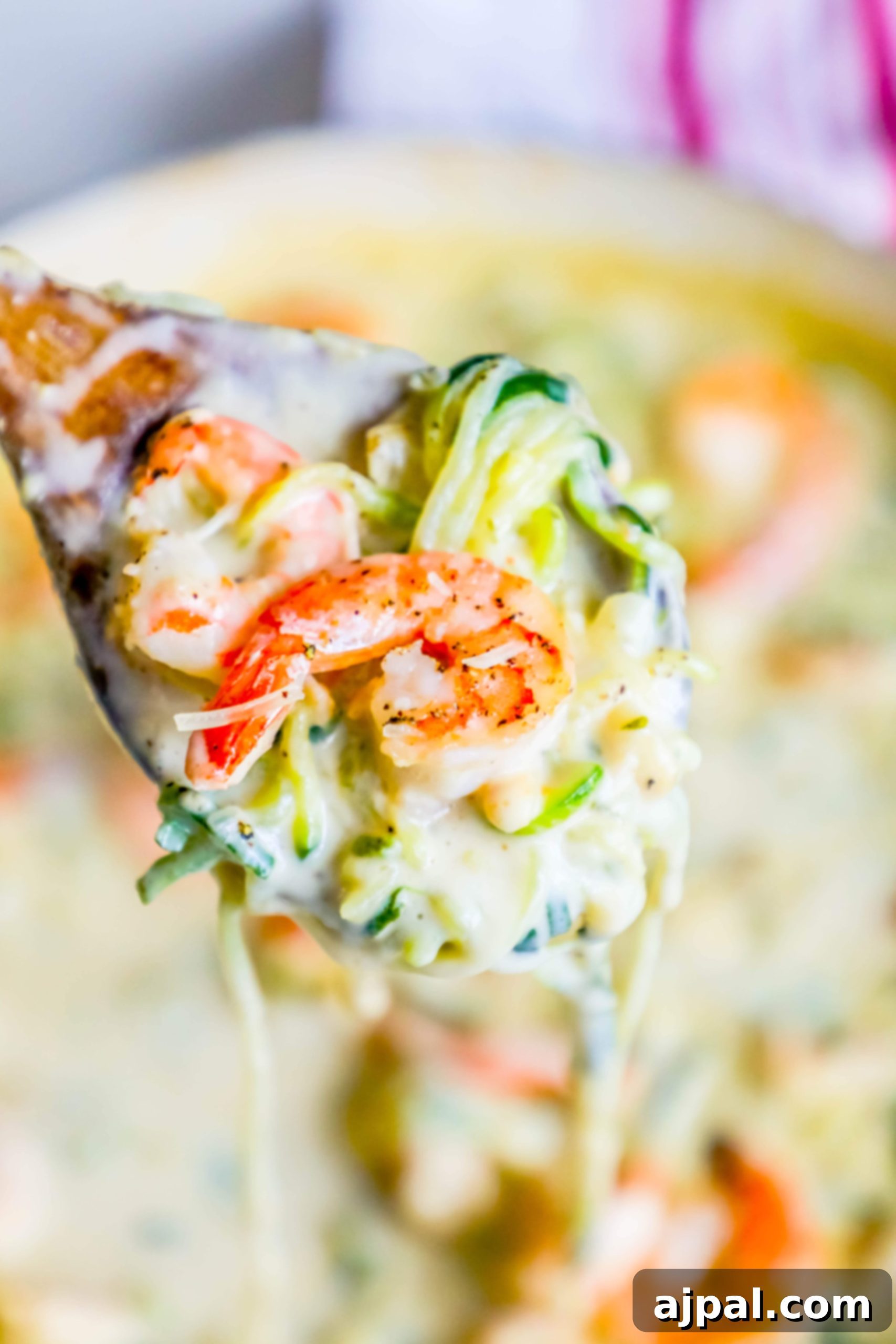 Velvet Shrimp Zoodle Alfredo 3 shrimp in a creamy sauce with noodles made out of zucchini on a spoon