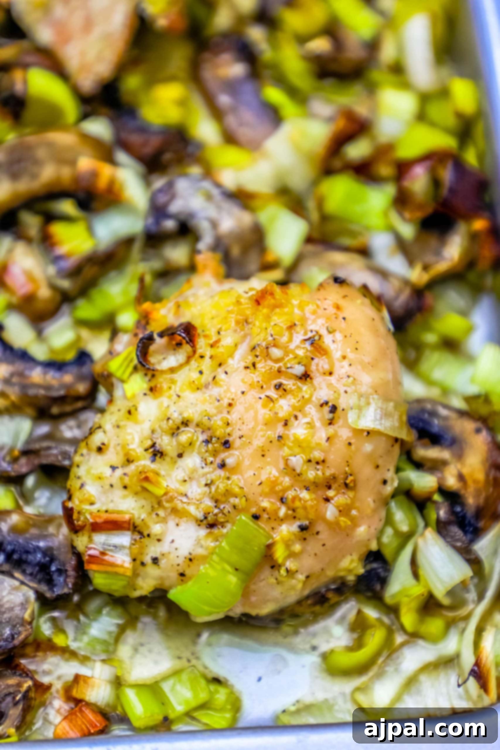 Easy sheetpan oven roasted chicken and leeks dinner recipe A beautifully presented sheet pan meal with golden roasted chicken thighs, softened leeks, and mushrooms, garnished with fresh herbs.