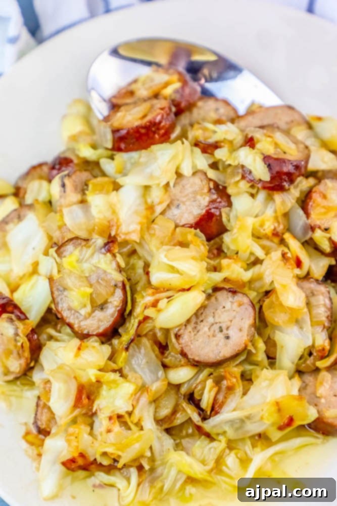 Sausage and cabbage in a bowl with a spoon – The Best Pan Fried Cabbage and Sausage Ever.